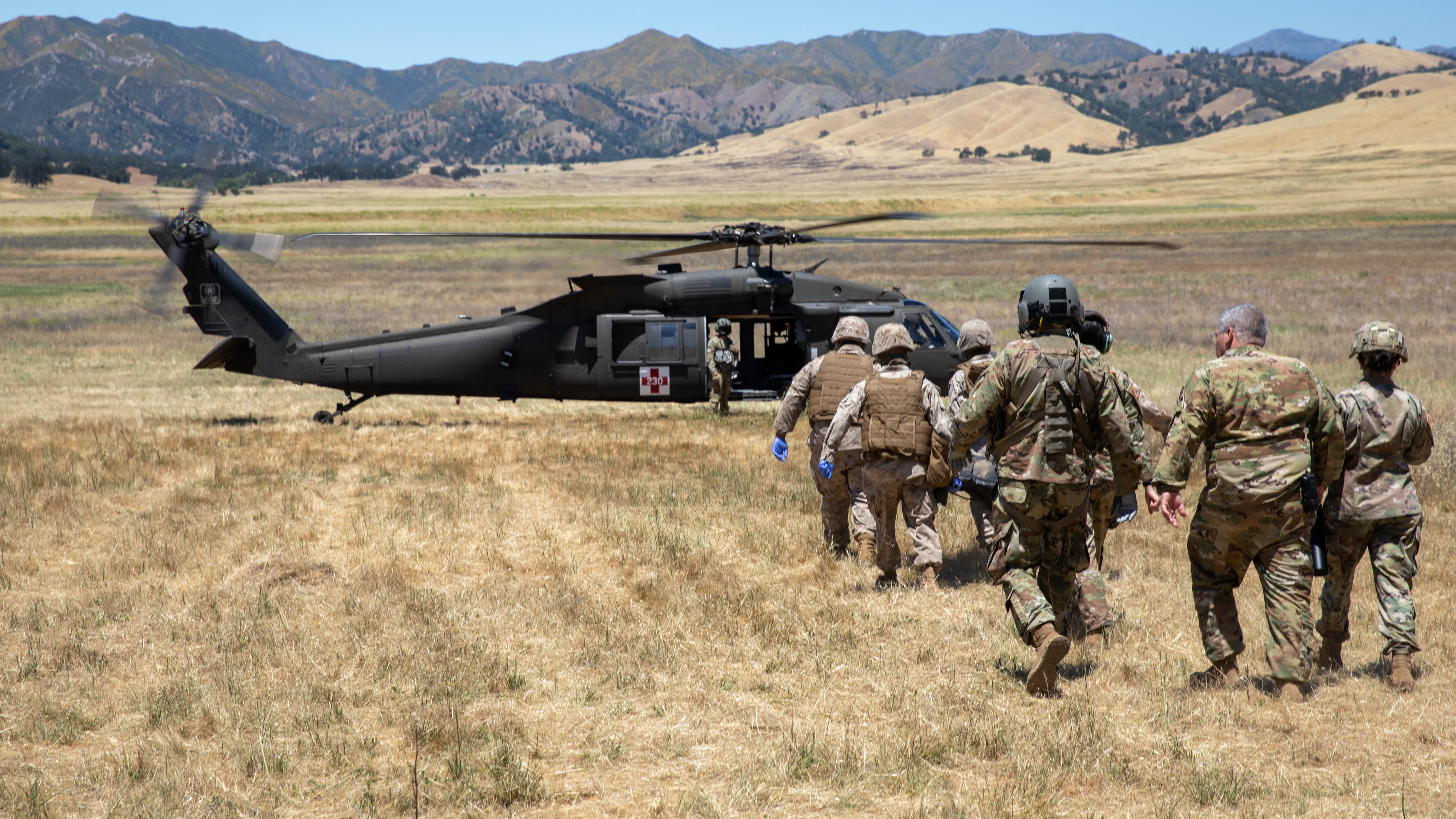 Military medics walking towards helicopter with stretcher