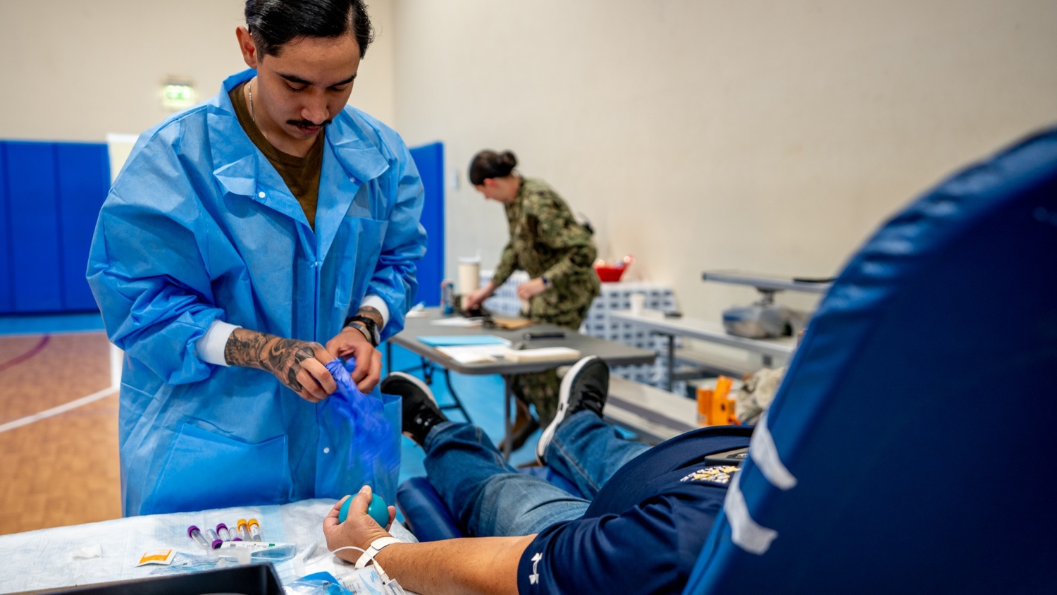 Staff member takes service member's blood during donor drive