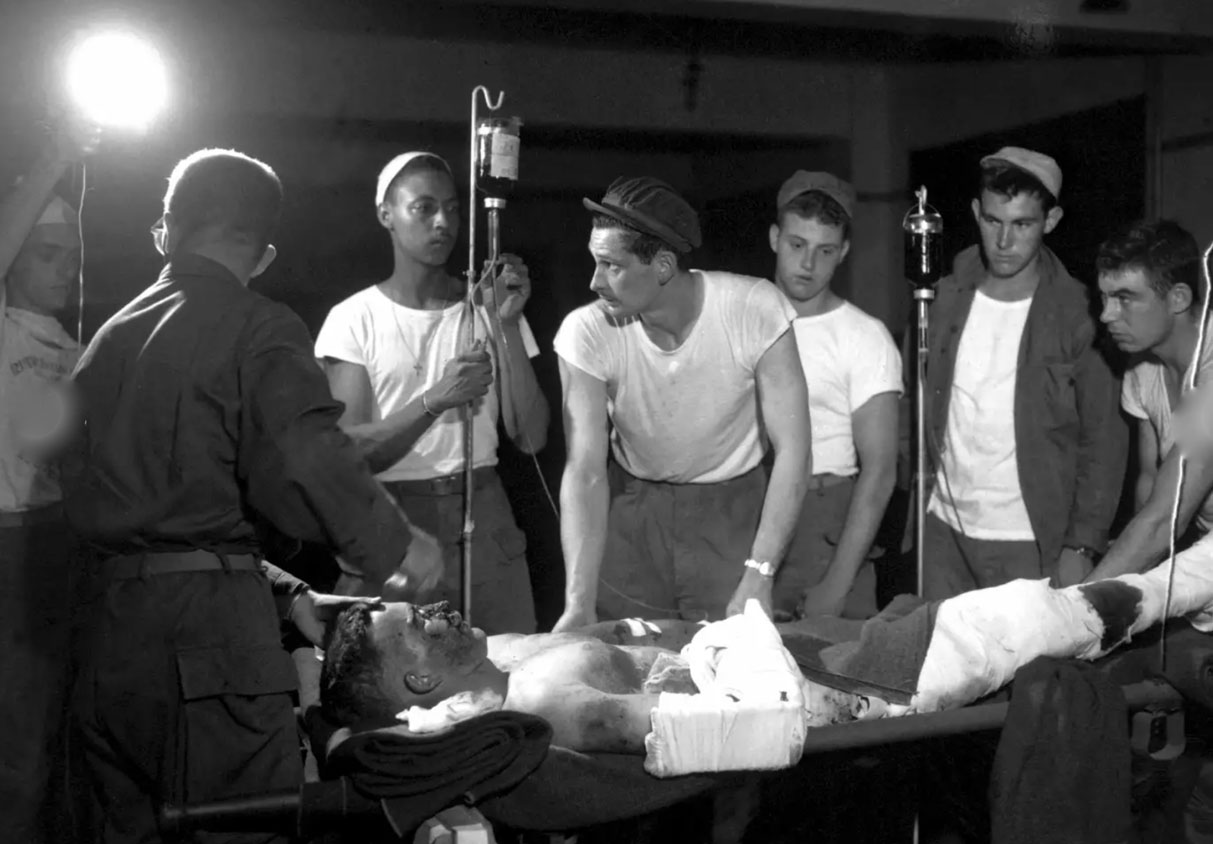 Wounded soldier on a bed surrounded by medical personnel