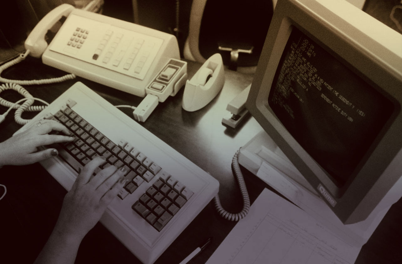 Woman with nail polish typing on an old-school keyboard and computer