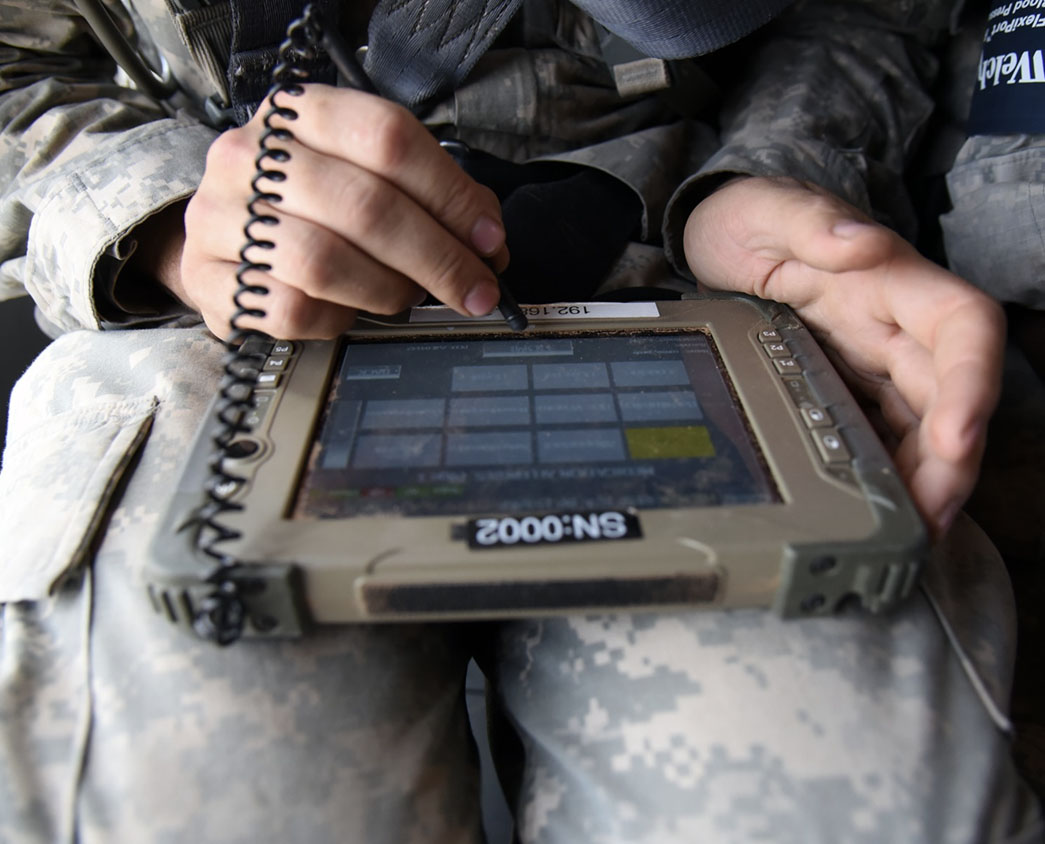 Soldier with a tablet on his lap, entering information with attached stylus