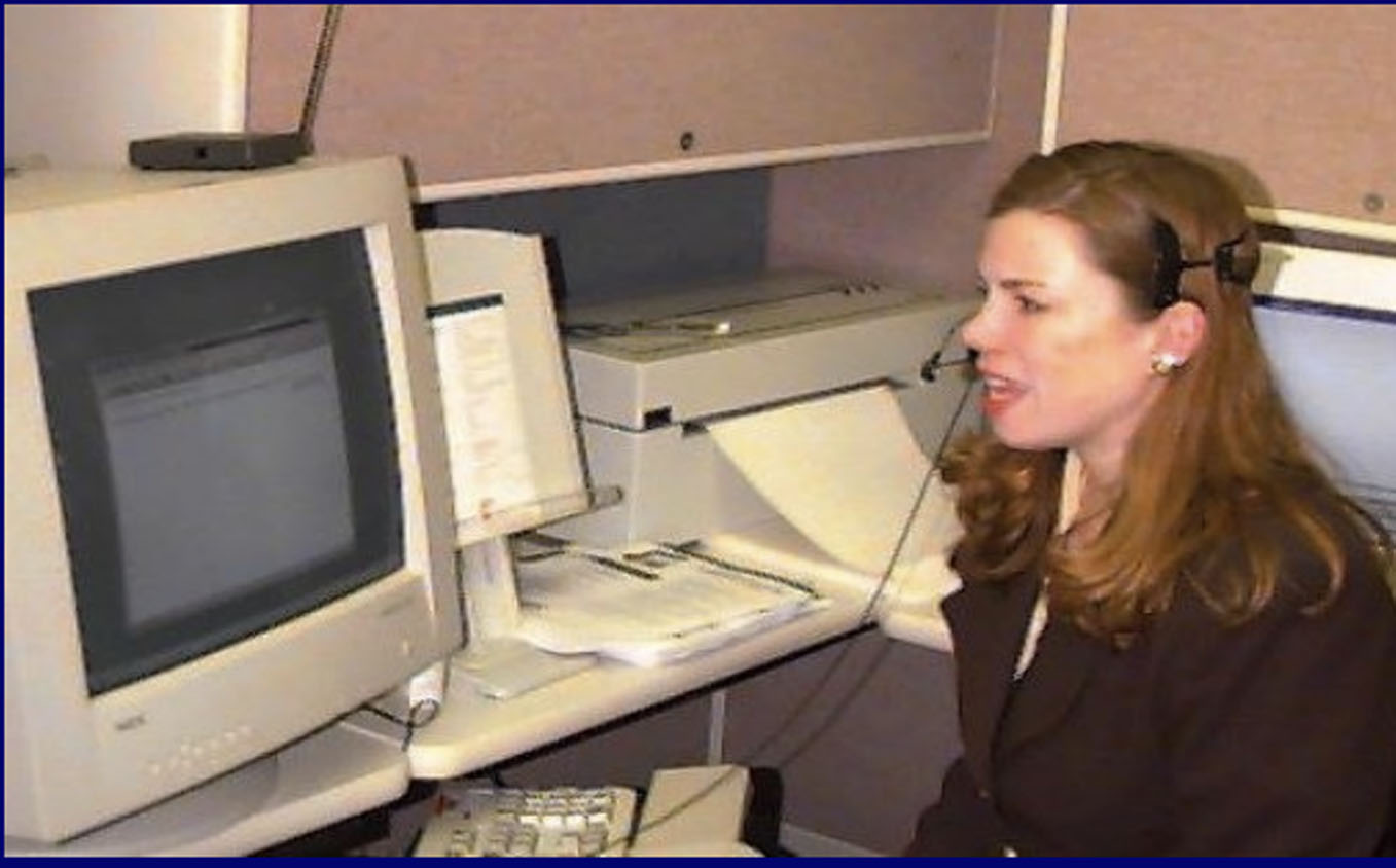 Woman with headset sitting at a desk with a computer and a printer