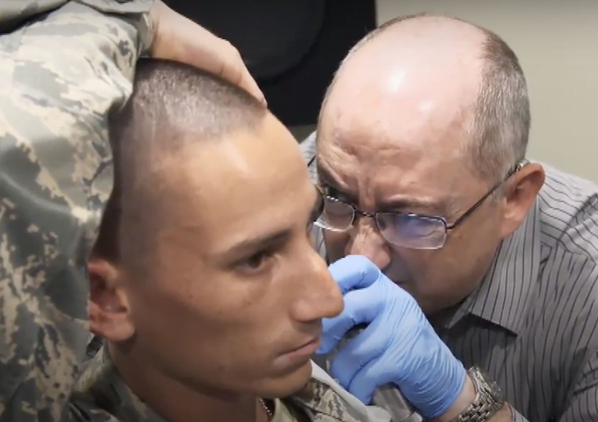 Doctor using otoscope to look into a soldier's ear