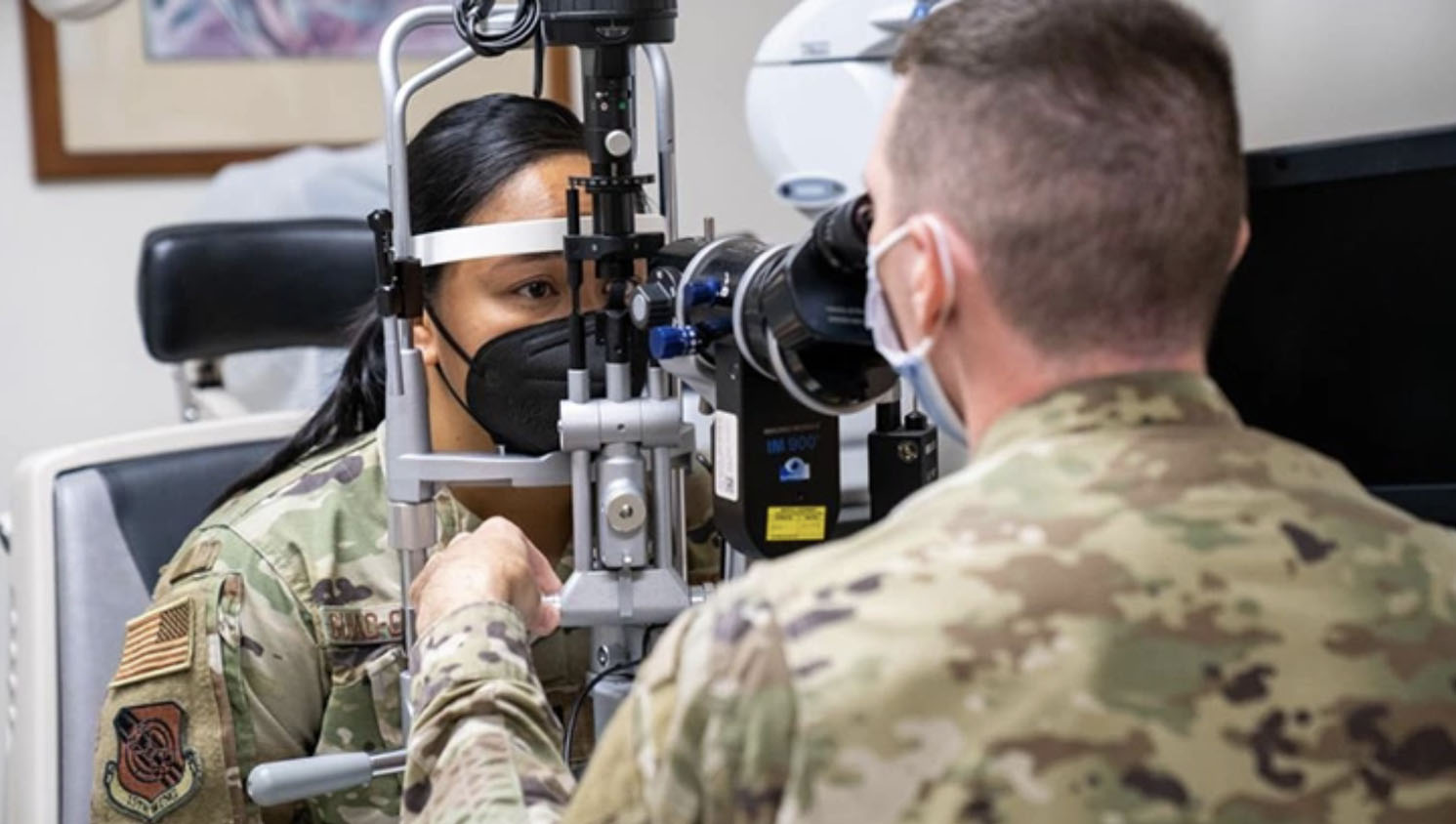 Military optometrist looking at soldier's eyes through ophthalmoscope
