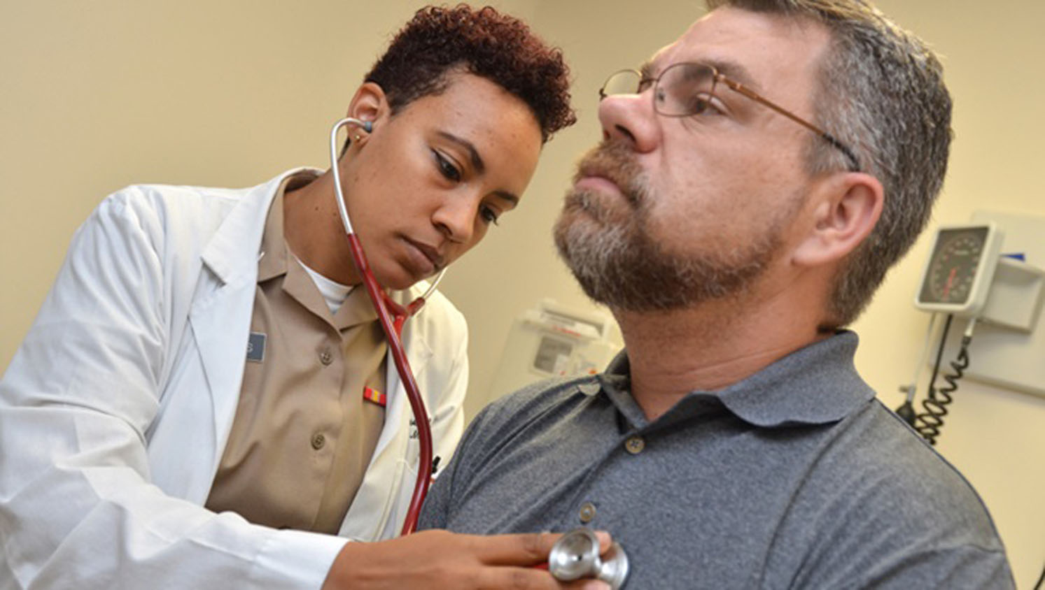 Medical personnel using a stethoscope to listen to a man's heart