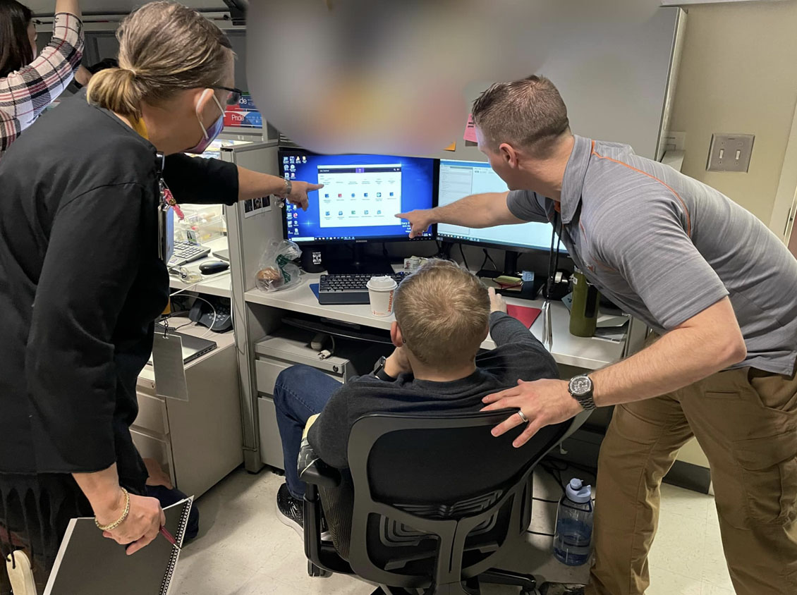 Three military personnel pointing to an image on a computer screen