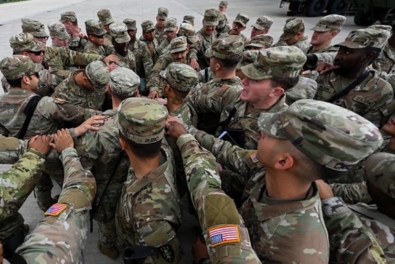 Group of soldiers in a circle reaching in and touching fists