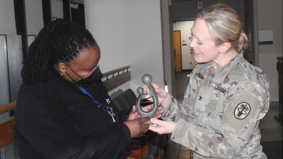 Two military personnel holding an award and smiling