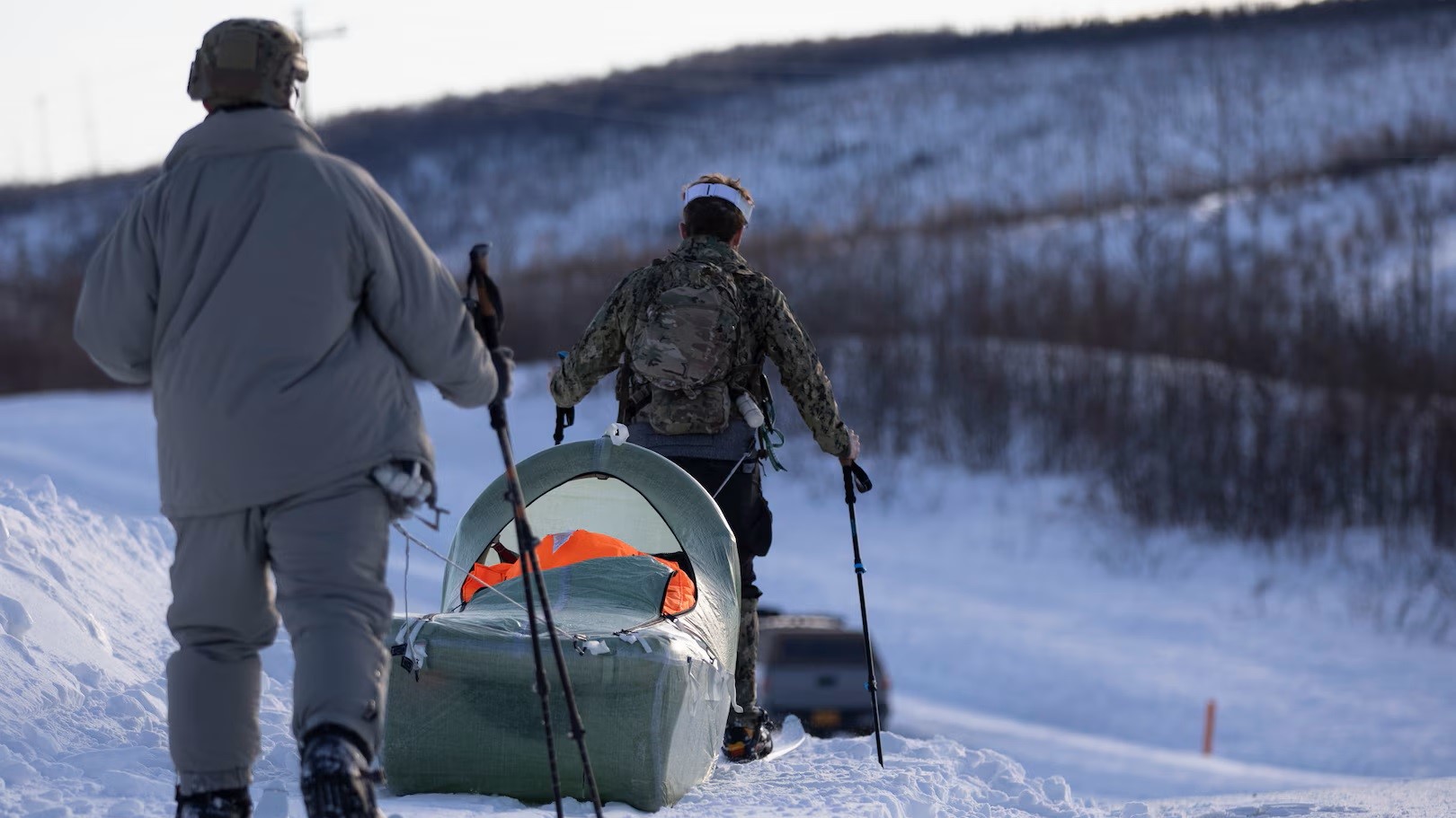 Two soldiers pull an inflatable sled designed to move and protect wounded personnel