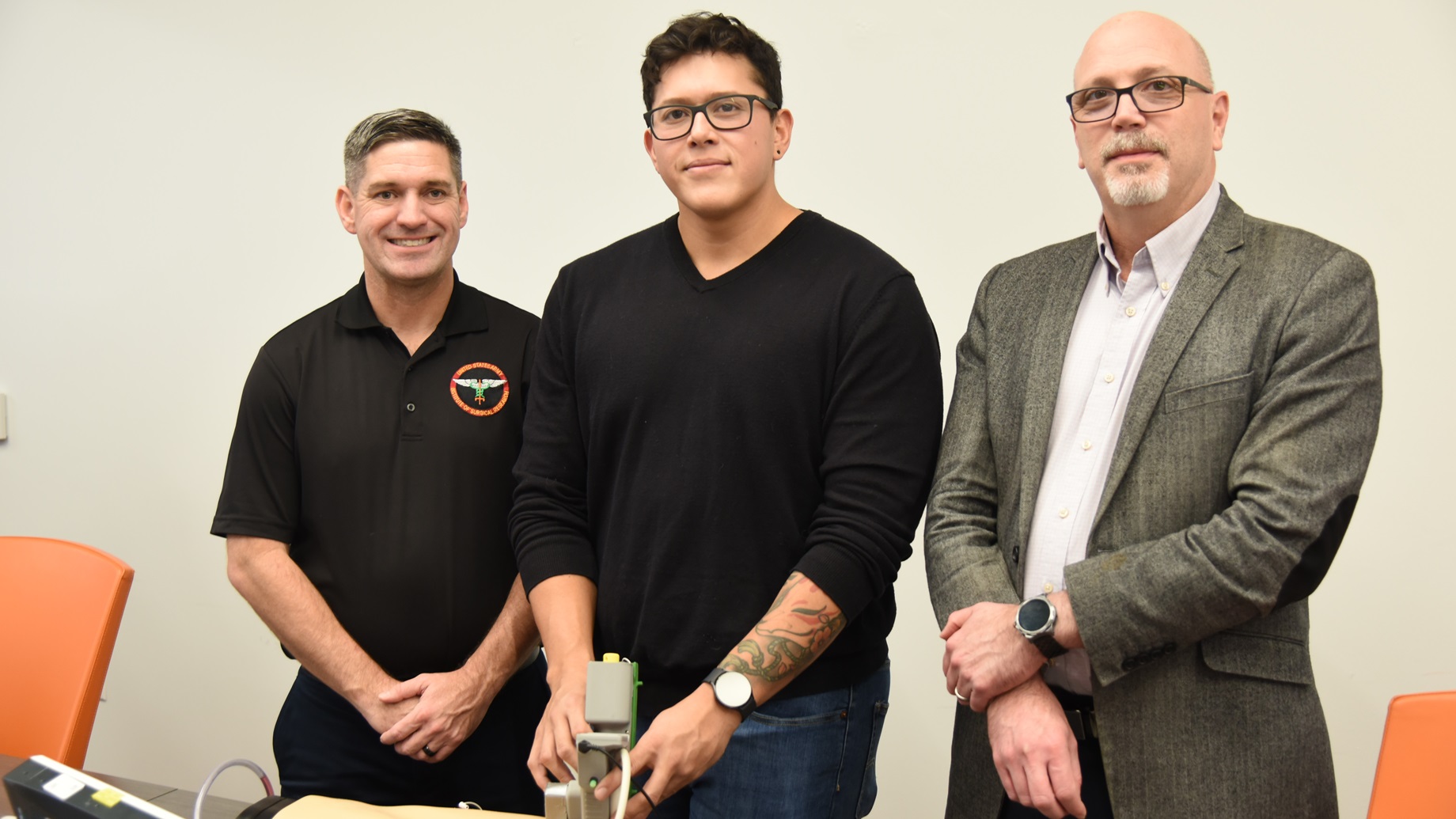 U.S. Army Institute of Surgical Research teammates Lt. Col. Brian Kirkwood, left, a comprehensive dentist and chief Artificial Intelligence officer with Organ Support and Automation Technologies team, engineer Carlos Bedolla, and science lead Dr. Jose Salinas pose with the prototype of an AI-enhanced ultrasound nerve block device developed by USAISR in partnership with MIT Lincoln Laboratory, during a demonstration at the VelocityTX biotechnology incubator in San Antonio, Texas, in November 2024.