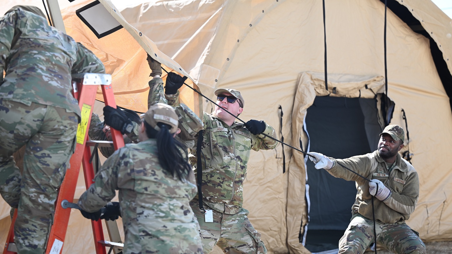 U.S. Air Force 1st Lt. Samuel Houpt, left, 8th Healthcare Operations Squadron medical service core officer, and Staff Sgt. Kemosi Hatten, 8th Medical Group personnel reliability program noncommissioned officer in charge, lift the internal section of a medical tent into position during an expeditionary medical support health response team training at Kunsan Air Base, Republic of Korea, Feb. 13, 2025. EMEDS HRT training is critical for maintaining the preparedness of medical personnel who might be deployed in support of military operations or emergency response missions. (U.S. Air Force photo by Staff Sgt. Nicholas Ross)