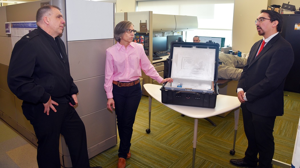 Andres Martinez Murillo, a biomedical engineer assigned to Combat Casualty Care and Operational Medicine, Naval Medical Research Unit (NAMRU) San Antonio, joined by research scientist Tarea Burton, briefs the capabilities of a portable ozone sterilizer to Rear Adm. Matthew Case, the Defense Health Agency’s (DHA) acting assistant director, Health Administration (AD-HCA) at the Battlefield Health and Trauma Research Institute.