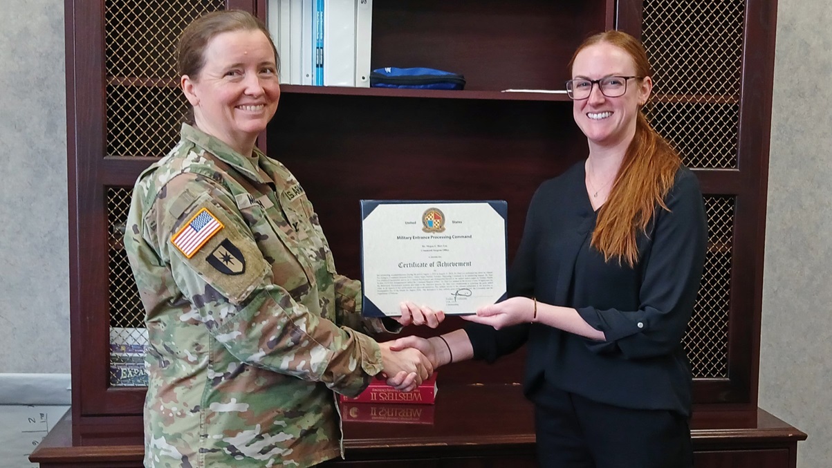 Army Col. Megan McKinnon, command surgeon, presents Dr. Megan Hart Lee, lead clinical psychologist, with an award for her service and achievements in developing the USMEPCOM Behavioral Health Consulting program. The Behavioral Health Consulting program at USMEPCOM has significantly improved processing efficiency and reduced wait times for military applicants needing behavioral health consultations. (Photo by Derrik Noack.)
