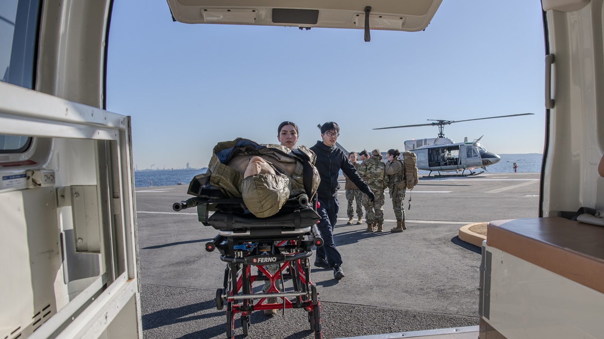 U.S. Navy members assigned to the Naval Hospital Yokosuka push a simulated patient on a litter during casualty evacuation training at Yokosuka Naval Station, Japan, Feb. 20, 2025. The rapid-response airlift capability replaces an approximately two-hour ambulance ride to Naval Hospital Yokosuka with a 30‑minute flight. (U.S. Air Force photo by Staff Sgt. Spencer Tobler)