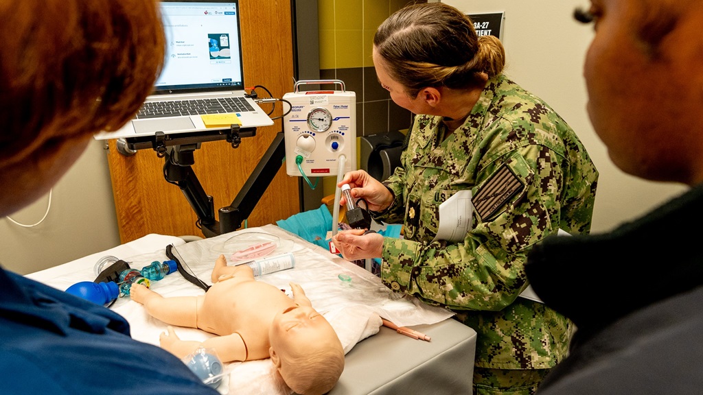 Lt. Cmdr. Brandi Gibson demonstrating equipment set up and components of the Resuscitation Quality Improvement (RQI) simulator for the Neonatal Resuscitation Program (NRP) to learners. The addition of this advanced training tool underscores the hospital’s commitment to improving neonatal care and aligns with ongoing efforts by Navy Medicine and the Defense Health Agency (DHA) to enhance medical readiness and patient outcomes. (U.S. Navy photo by Hospital Corpsman 1st Class Petty Officer Carlos Villegas).