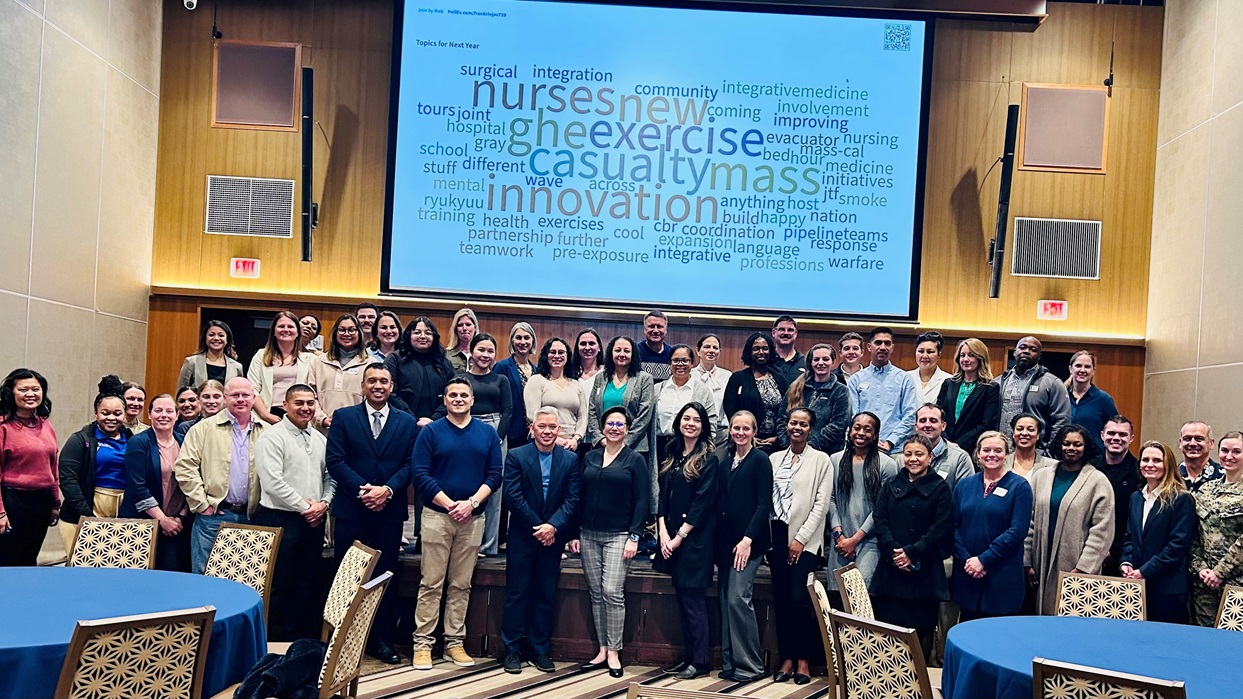 Group of people standing in an auditorium under a word cloud image of nursing-related terms