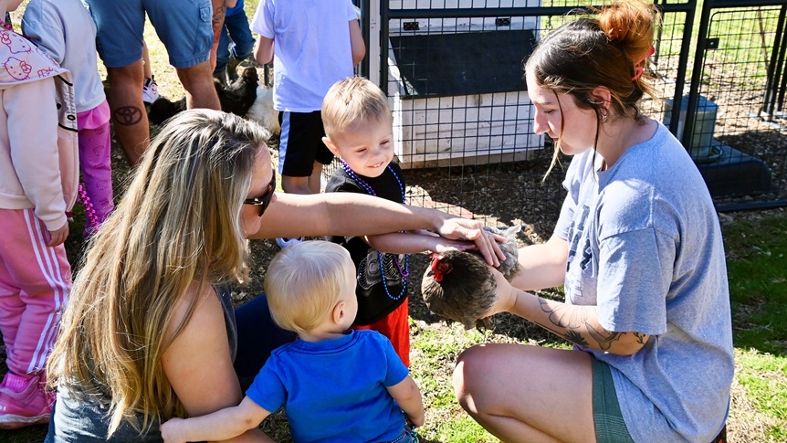 Alisha Pichette (left) and Sydney Gallegos (right) introduce their sons to one of the chickens during a local Courir de Mardi Gras “Chicken Chase." The family-friendly event gave military children and parents a chance to engage in a cherished Louisiana tradition together while stationed at the Joint Readiness Training Center and Fort Johnson.