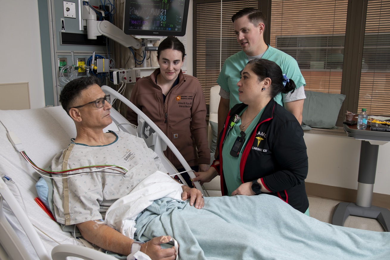 Army Col. Gustavo Moreno discusses his care plan with Army Capt. (Dr.) Aitana Rizzo, internal medicine resident, Air Force Capt. (Dr.) William Colthorpe, internal medicine resident, and Victoria Morgan, registered nurse, at Brooke Army Medical Center, Joint Base San Antonio – Fort Sam Houston, Texas, June 18, 2025. TRICARE beneficiaries can request to be taken directly to BAMC for care, or they can request transfer to BAMC by calling 210-916-2733. (DoD photo by Jason W. Edwards)