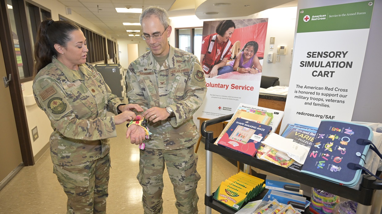 Maj. Bonnie Sgroi, 60th Inpatient Squadron clinical nurse specialist, demonstrates one of the sensory tools to Col. Patrick Parsons, 60th Medical Group commander, during the unveiling of a new Sensory Simulation Cart at David Grant USAF Medical Center, Travis Air Force Base, California, July 16, 2025