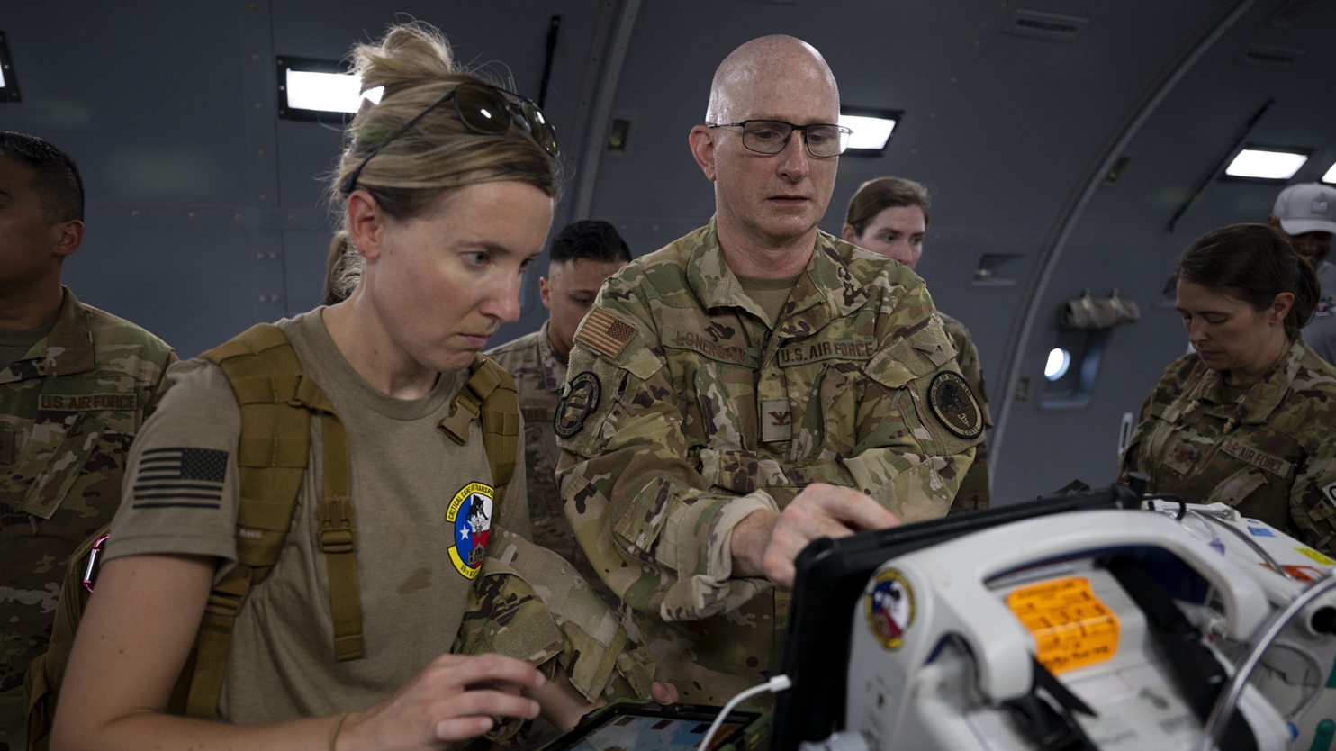 Air Force Maj. Amber Hadjis, En Route Critical Care Pilot Unit manager, and Col. (Dr.) Terence Lonergan, Critical Care Air Transport Team Pilot Unit medical director and Brooke Army Medical Center Extracorporeal Membrane Oxygenation director, program a simulation scenario during a Validated Assessment Program for Operational Readiness Critical Care Air Transport training flight, Aug. 21, 2025. The Vapor Trails program allows CCAT teams to conduct live training flights, as opposed to using static simulations. (DoD photo by Jason W. Edwards)