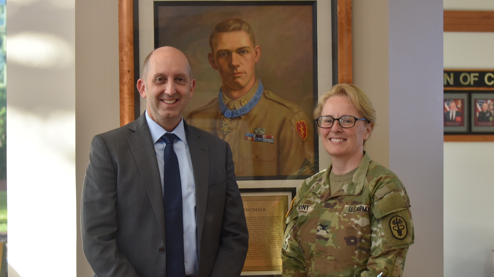 Dr. Stephen Ferrara, acting Assistant Secretary of Defense for Health Affairs, poses with Col. Stephanie Mont, Hospital Commander, by a portrait of Medal of Honor recipient Pfc. Bryant Homer Womack who the hospital is named after, during his visit to Womack Army Medical Center, Fort Bragg, September 3, 2025. Ferrara is visiting WAMC to collect firsthand feedback to understand local issues and successes, which helps him advocate for the staff and resources needed. (Defense Health Agency photo by Keisha Frith)