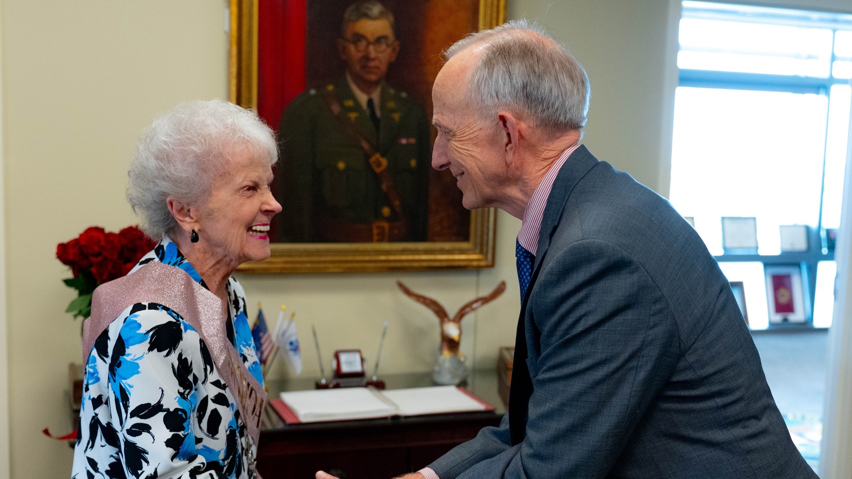 Dr. David Smith, acting principal deputy assistant secretary of Defense for Health Affairs and acting director of the Defense Health Agency, presents a coin to Carolyn Putnam, executive secretary to the commander, at Brooke Army Medical Center, Joint Base San Antonio-Fort Sam Houston, Texas, July 21, 2025. Putnam was recognized for her remarkable dedication to BAMC to include a career in civilian service spanning over 70 years. (DoD photo by James Camillocci)