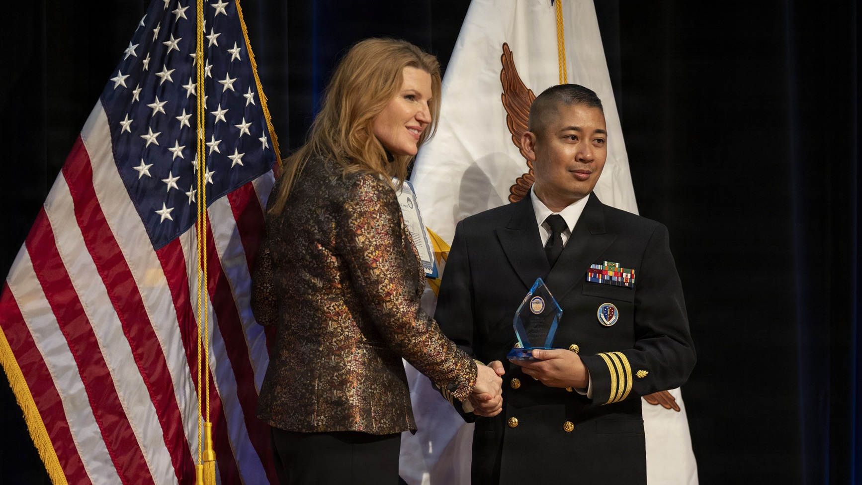Department of War Chief Information Officer Kirsten Davies presents the Defense Health Agency Individual Longitudinal Exposure Record Program Management Office with the Team Gold Award at the 25th Department of War CIO Annual Awards Program ceremony held in the Pentagon, Arlington, Virginia, Feb. 23, 2026. Cmdr. Raben B. Talvo, product officer for the Individual Longitudinal Exposure Record Program Management Office, accepted the award on behalf of the team. (Photo by Petty Officer 1st Class Alexander Kubitza/Office of the Secretary of War Public Affairs)