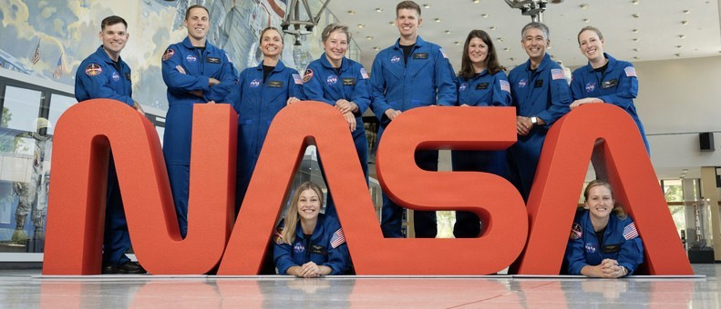 A group of astronaut candidates surround the word "NASA"