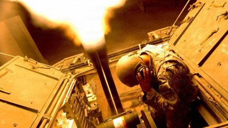 A U.S. Army Soldier holds his ears as he uses a 120mm Mortar Cannon in a Mortar Carrier Stryker vehicle to fire illumination flares over the city of Mosul, Iraq, on June 1, 2006.