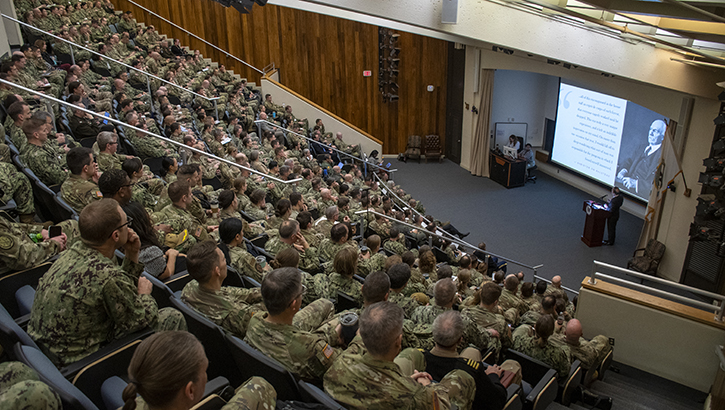 Large room of people in uniform with speaker