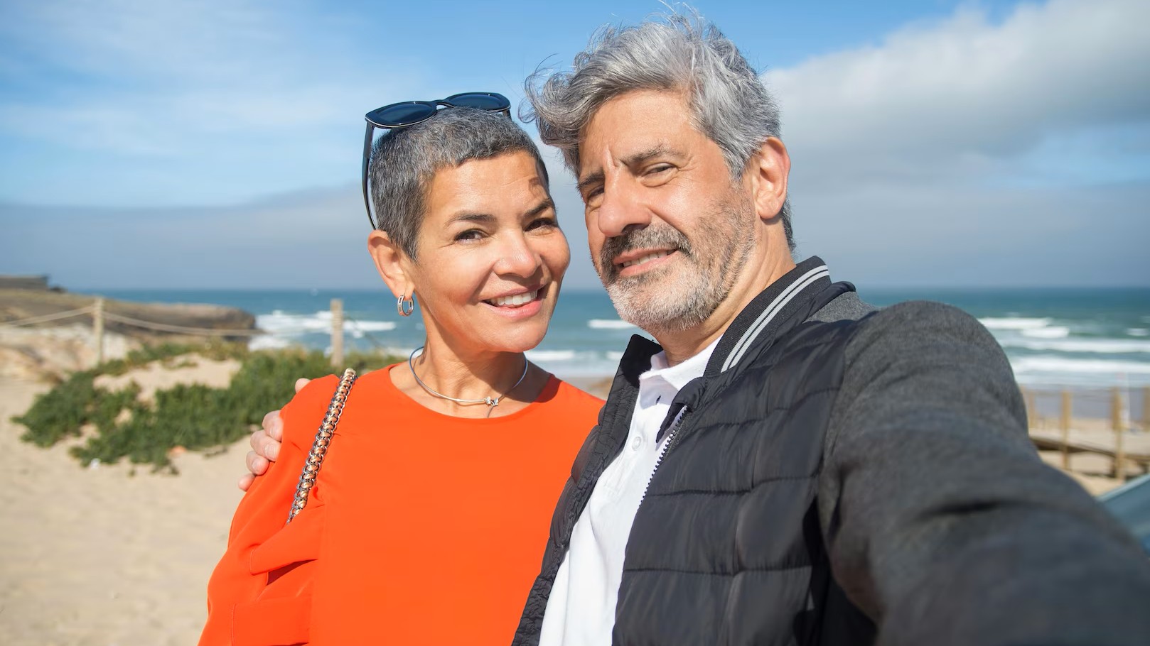 Smiling man and woman at a beach, taking a selfie