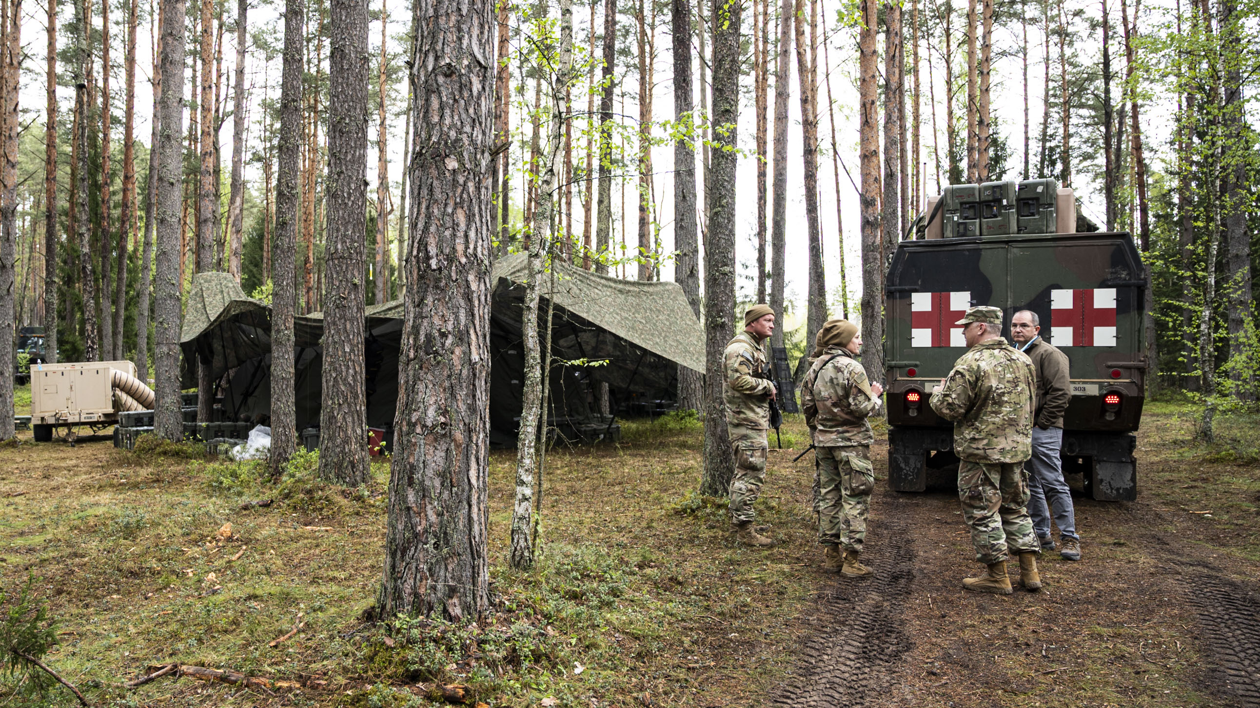 Medics gather in the forest behind truck with red cross