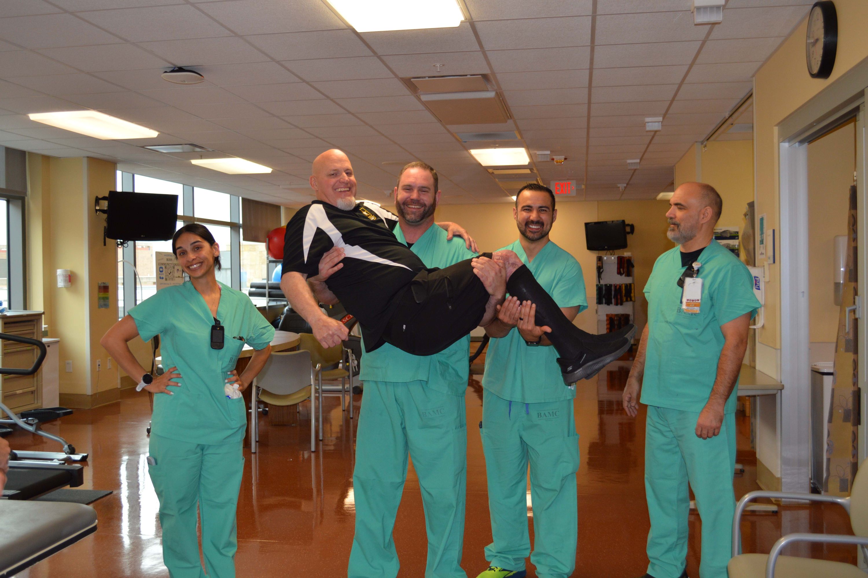 Physical Therapist Kyle Cunningham picks up burn survivor retired Army Master Sgt. Chris Hiatt during a visit to the U.S. Army Institute of Surgical Research Burn Center located within Brooke Army Medical Center, Joint Base San Antonio-Fort Sam Houston, Texas